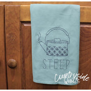 Light blue tea towel with a dotted teapot and STEEP, featuring Aunt Martha’s Sashiko Japanese embroidery