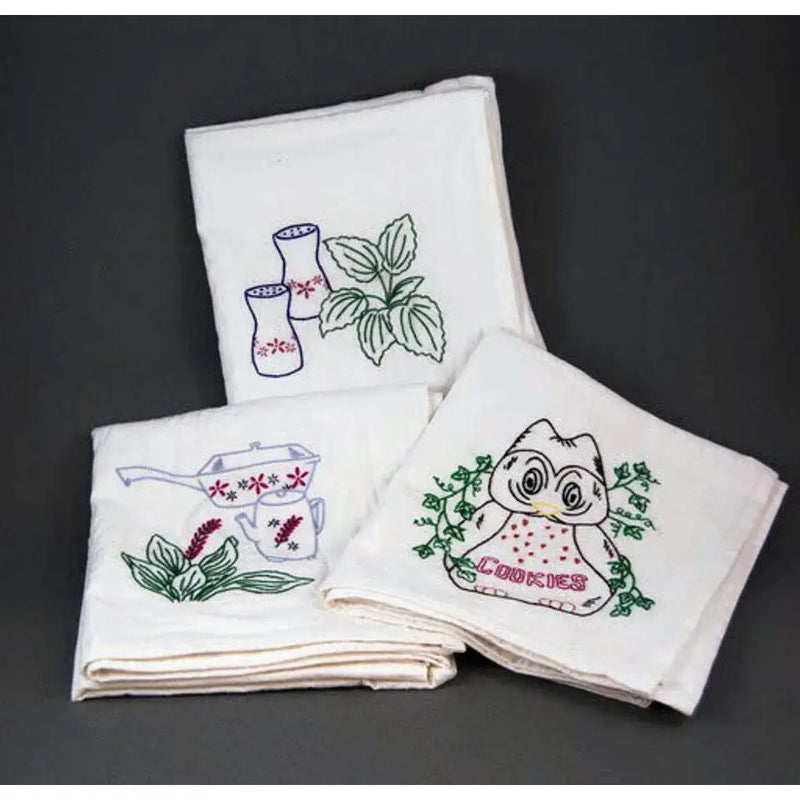 Set of embroidered white kitchen towels featuring floral and kitchenware designs from Aunt Martha’s