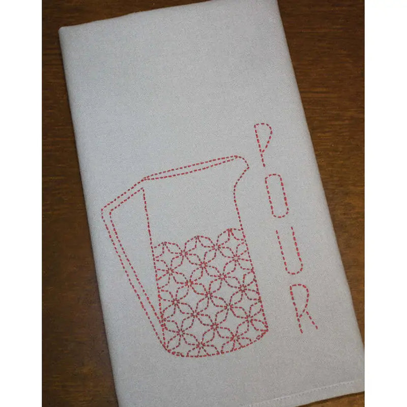 White tea towel with red pitcher design showcasing Sashiko Japanese embroidery by Aunt Martha’s